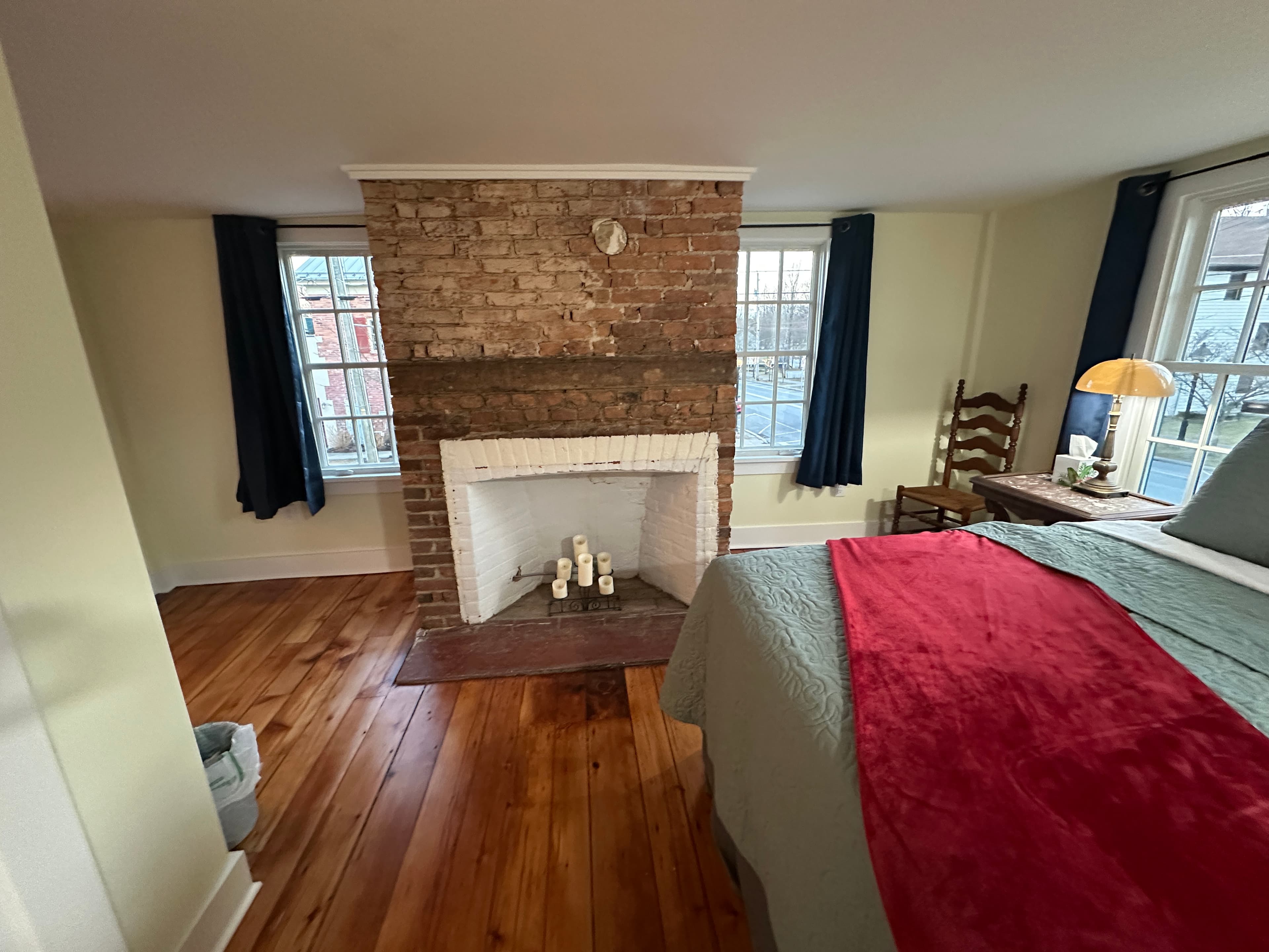 Guestroom with decorative fireplace, queen bed, and beautifully finished original hardwood floors
