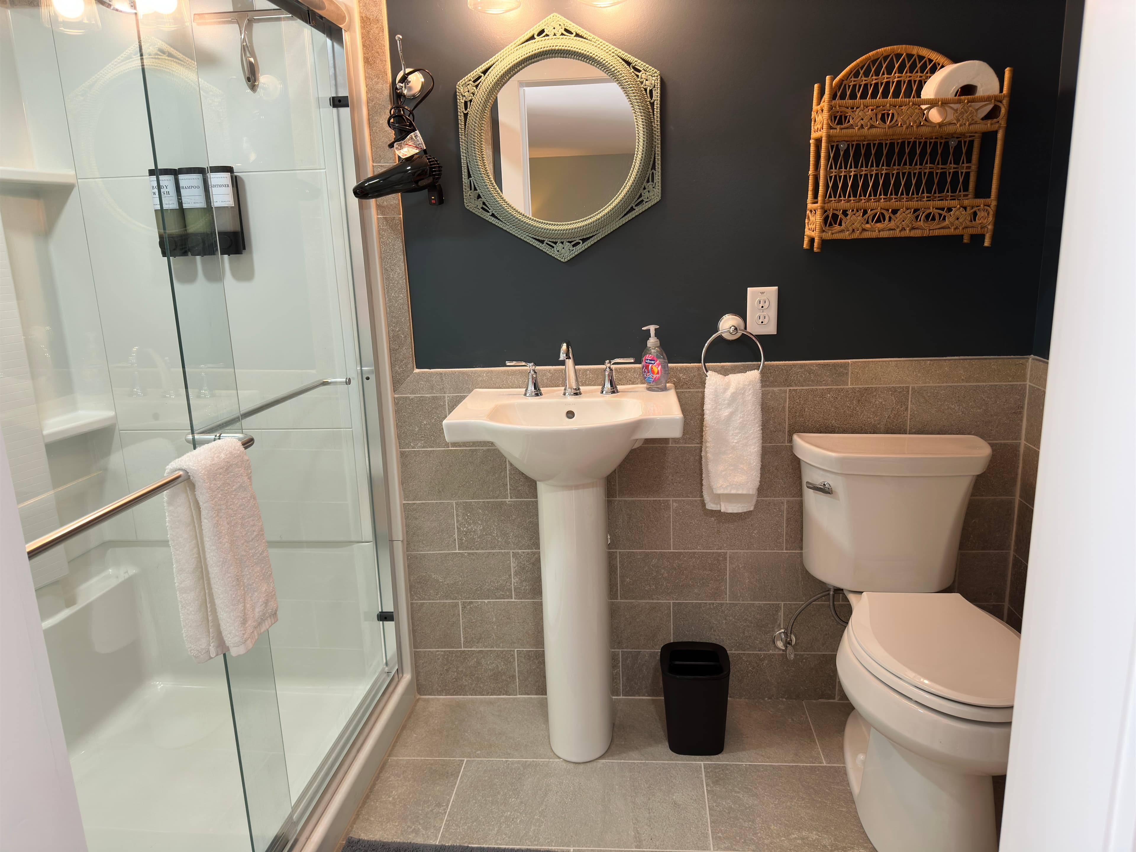 Pristine bathroom with white toilet, pedestal sink, and walk-in shower
