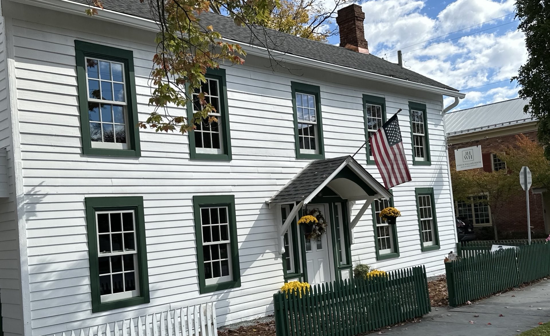 Exterior of white two story house with brick fireplace chimney on the right.