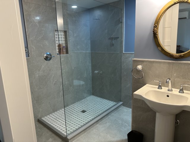 Bathroom with grey tile and glass shower door.